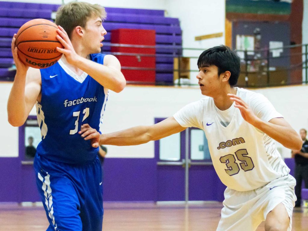 Two male athletes representing Facebook vs. Websites play basketball. 