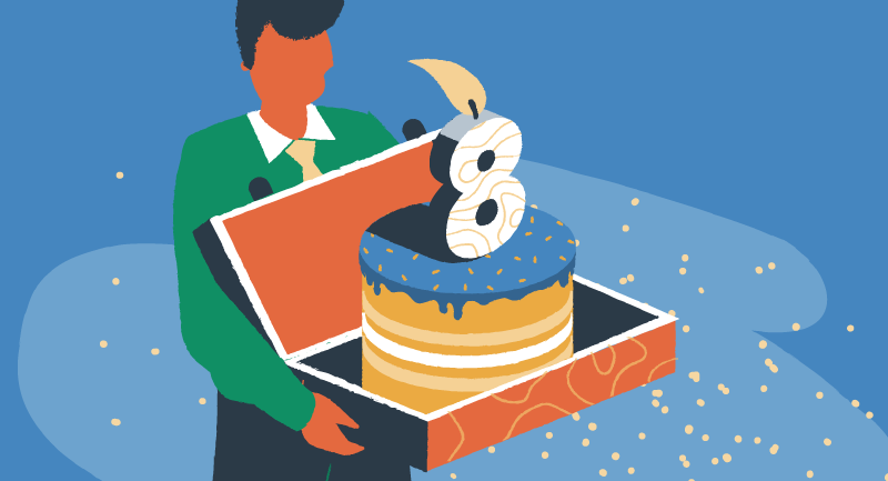 A man carries a birthday cake in a box with a burning candle on top the shape of the number 8.
